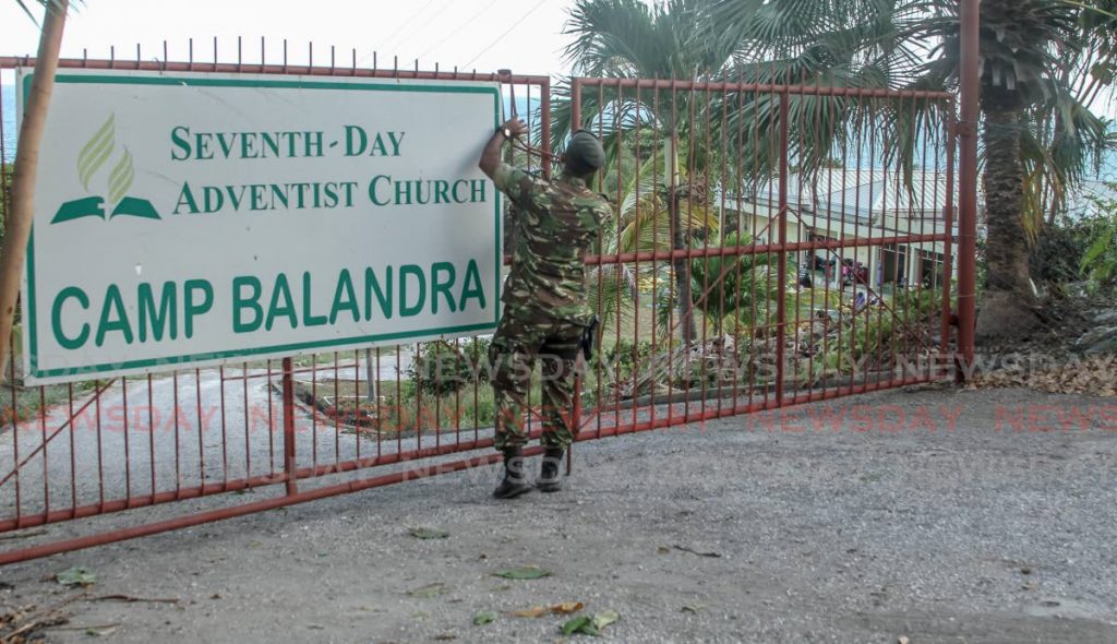 A soldier closes the gate at the Seventh-Day Adventist Church camp in Balandra, Toco on Wednesday.  PHOTO BY AYANNA KINSALE - Ayanna Kinsale