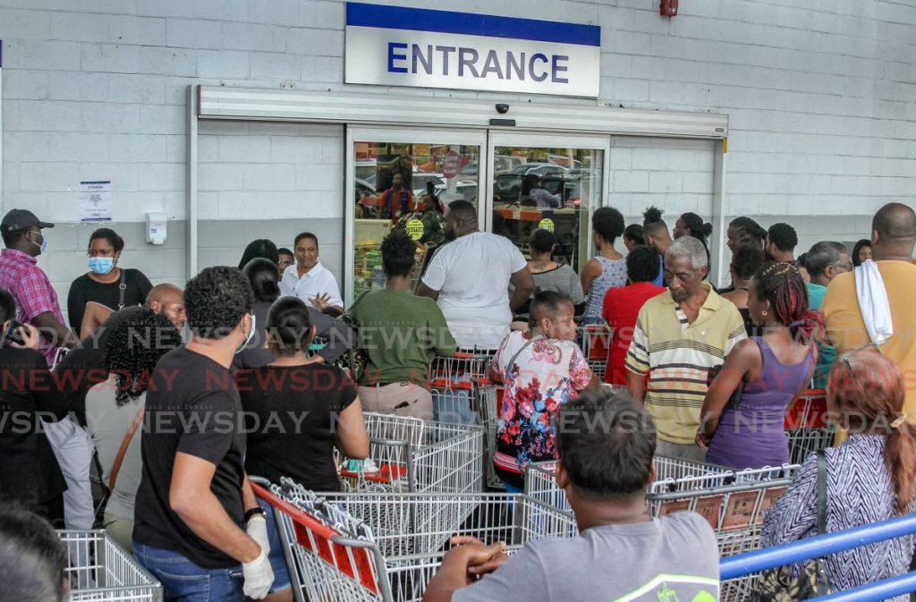 Customers wait to get in to PriceSmart, MovieTowne, Port of Spain, on Thursday. - Ayanna Kinsale