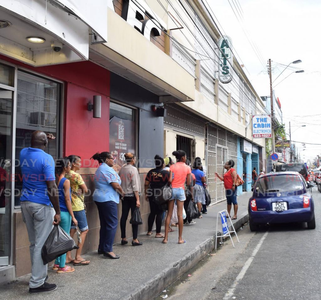 Customers wait their turn outside Ali's Pharmacy along Charlotte Street, Port of Spain on Friday. - Vidya Thurab