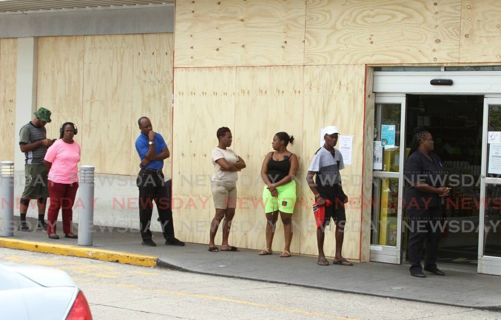 In this March 2020 file photo, customers stand outside Tru Valu, Long Circular Mall as they wait their turn to enter to purchase their items. - Photo by Ayanna Kinsale