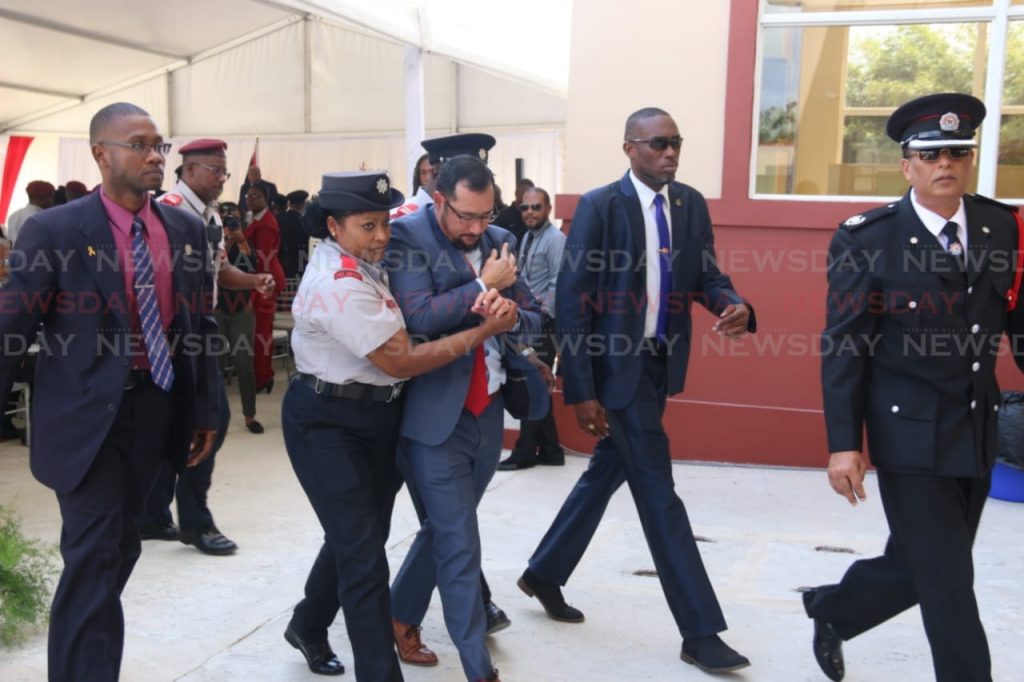Fire officers help National Security Minister Stuart Young to an ambulance after he fell at the opening ceremony for the Penal Fire Station on Clarke Road. Photo by Marvin Hamilton
