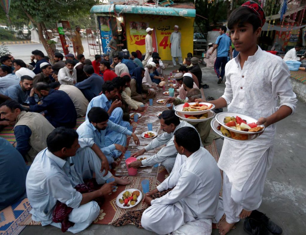 NOT THIS YEAR: For Muslims the world over, including in TT, scenes like this captured in 2019 in Pakistan, are common place during Ramadan at the breaking of fast. This year, because of the covid19 pandemic, most Muslims will be breaking fast and praying at home rather than at the mosque or out in public. AP PHOTO - AP