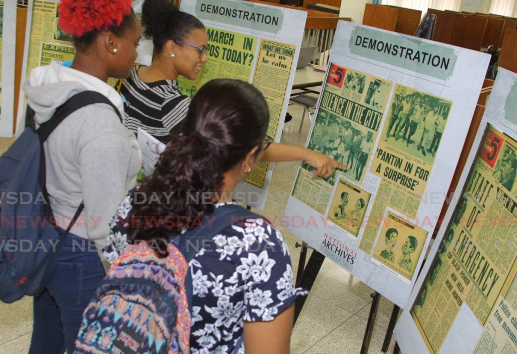 UWI students Jandell Romany, left to right, Kedisha Watson and Cyntia Bhajan discuss a display on the 50th anniversary of the Black Power Movement at the Alma Jordan Library on the St Augustine campus on March 9. UWI has announced changes to the dates for exams as the campus remains closed due to covid19 restrictions.  FIILE PHOTO/ROGER JACOB - 