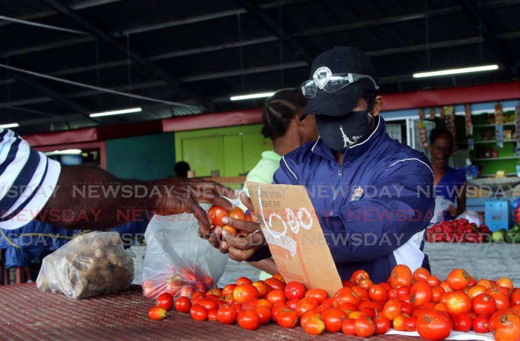 A man protects himself by wearing a mask as he buys tomatoes at the Central Market off the Beetham Highway in Port of Spain.  - Sureash Cholai