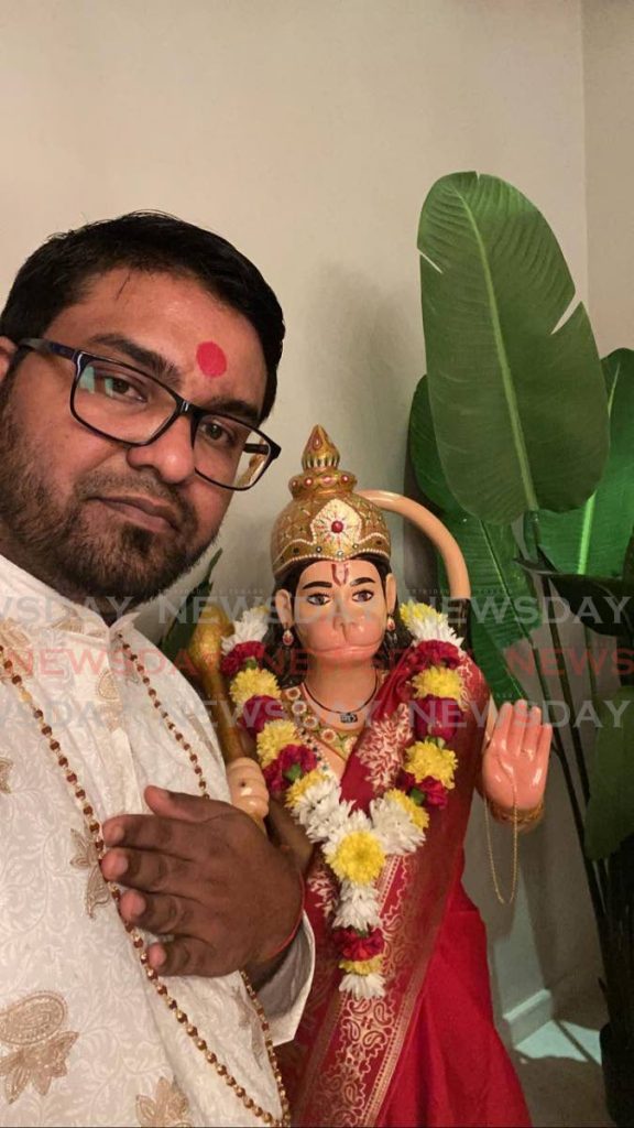 Pundit Sunil Seetahal stands next to the Hanuman murti. - 