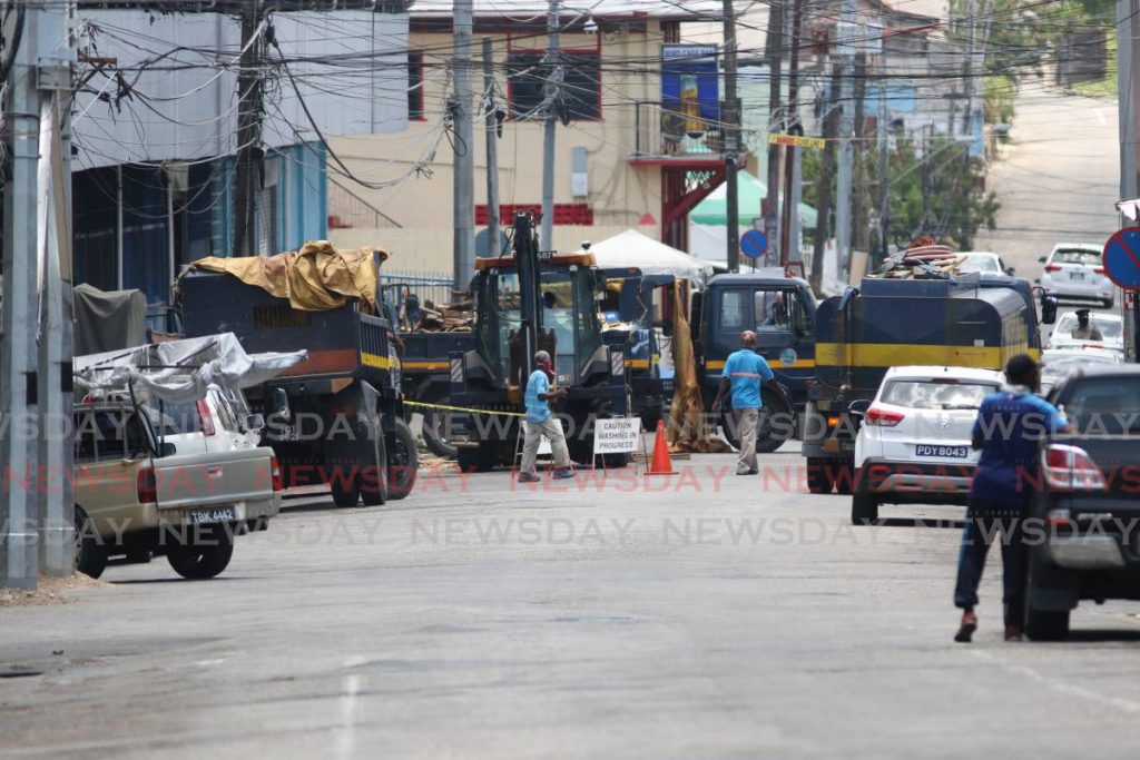 San Fernando City Corporation workers use excavators to load garbage onto trucks parked outside of the San Fernando Market on Mucurapo Street on Wednesday during a clean-up exercise. - MARVIN HAMILTON