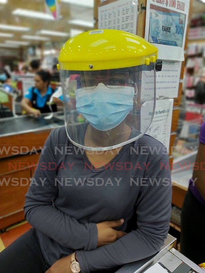 COVERED: A worker at Persads The Food King operates with full protective headgear and face mask. - 