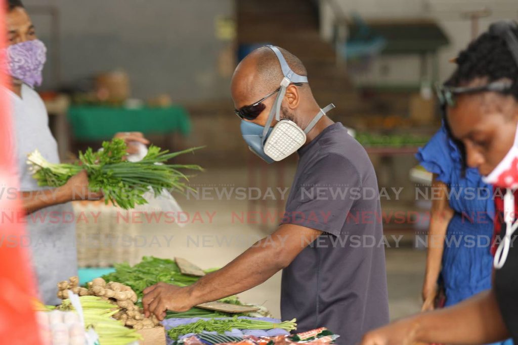 A customer at the San Fernando market adheres to the goverment's call to cover your face while in public.  - L Holder