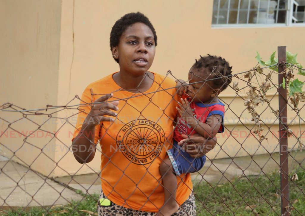 Kathleen Mulligan holds a small child while speaking to the media after her sister-in-law Annessa Gabrina Nero, 10, was knocked down on the Priority Bus Route, Macoya, on Sunday. - Ayanna Kinsale