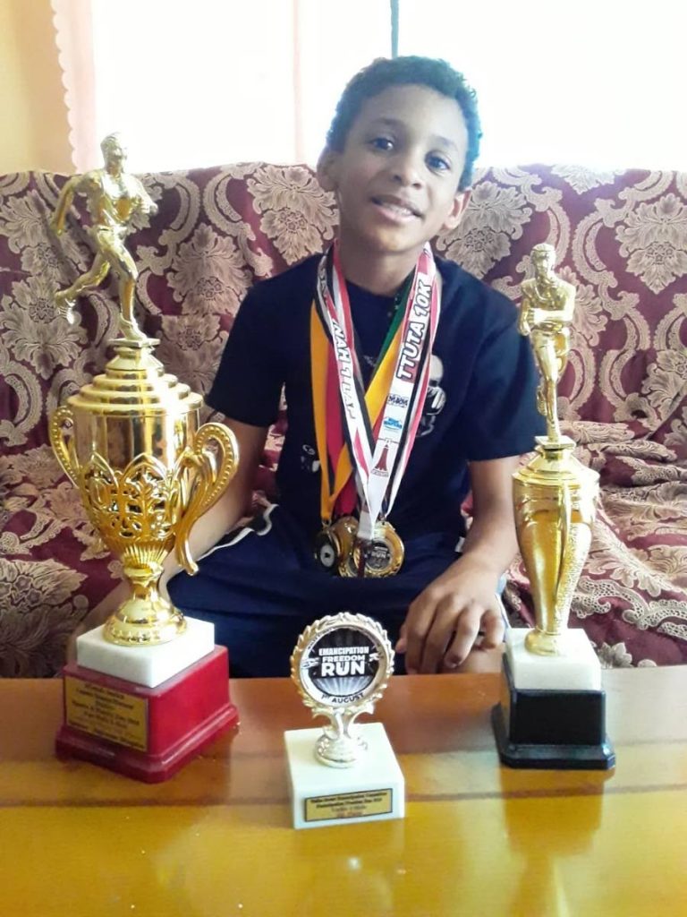 At just nine years old, Mikael Serrette displays some of his awards in long distance running.  - 