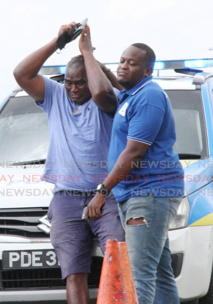 SORROW: Clive Alexis, left, is consoled by a relative as they arrived at the Solomon Hochoy Highway on Tuesday shortly after Alexis’ wife Karen was killed in an accident. 
PHOTO BY VASHSTI SINGH - 