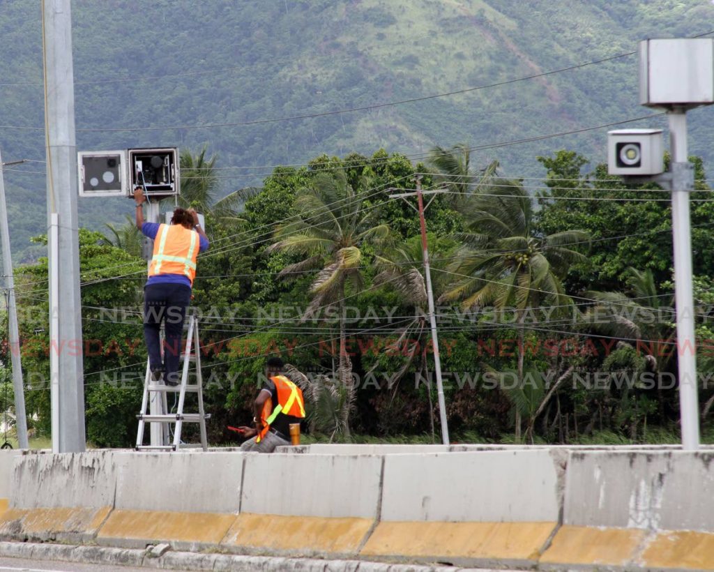 Technicians install a camera along the Churchill Roosevelt Highway, one of the devices to be used to catch traffic offenders. - ANGELO MARCELLE