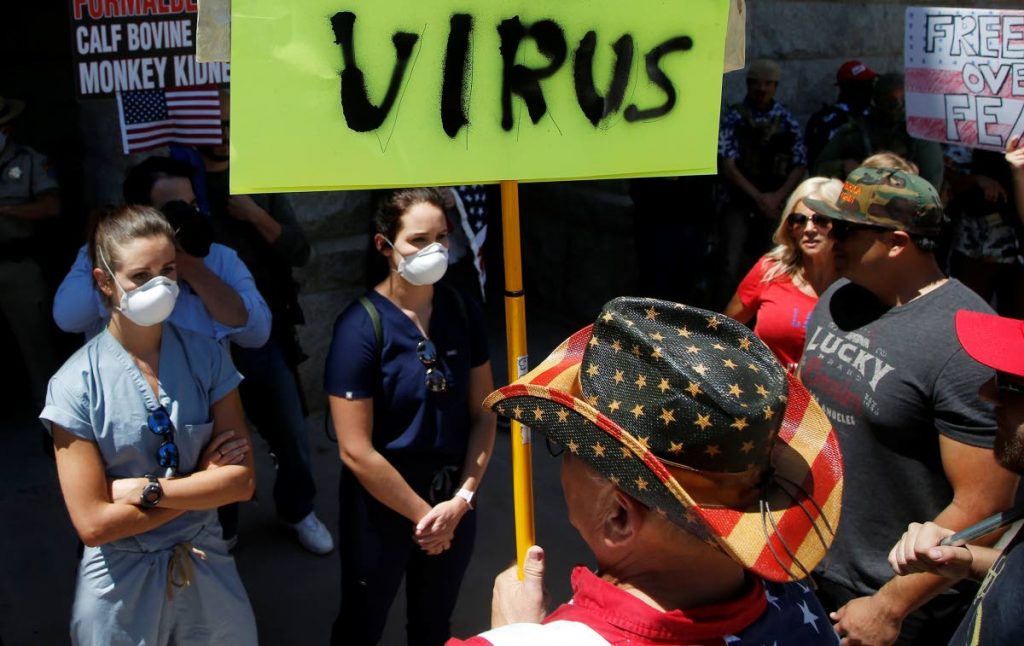Caregivers stand in front of protesters at the main entrance to the Arizona Capitol at a rally to 're-open' Arizona against the governor's stay-at-home order due to the coronavirus on April 20, 2020, in Phoenix.  - AP PHOTO