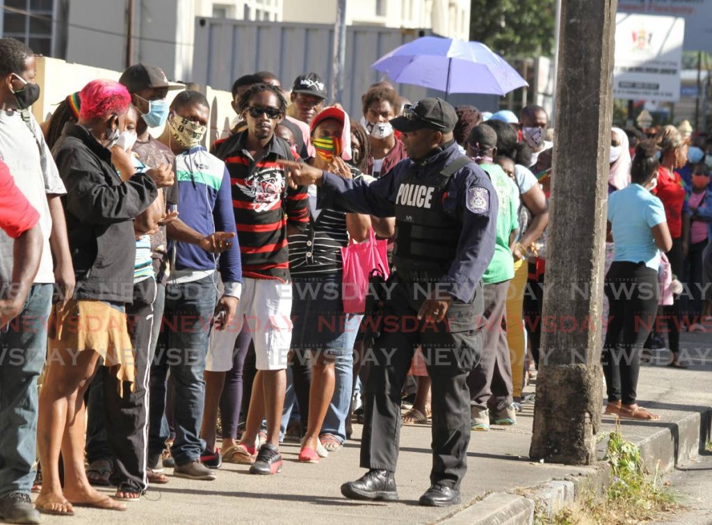 A police officer ensures there is order at the Living Waters Community Centre, Frederick Street, Port of Spain, last Friday. - Ayanna Kinsale