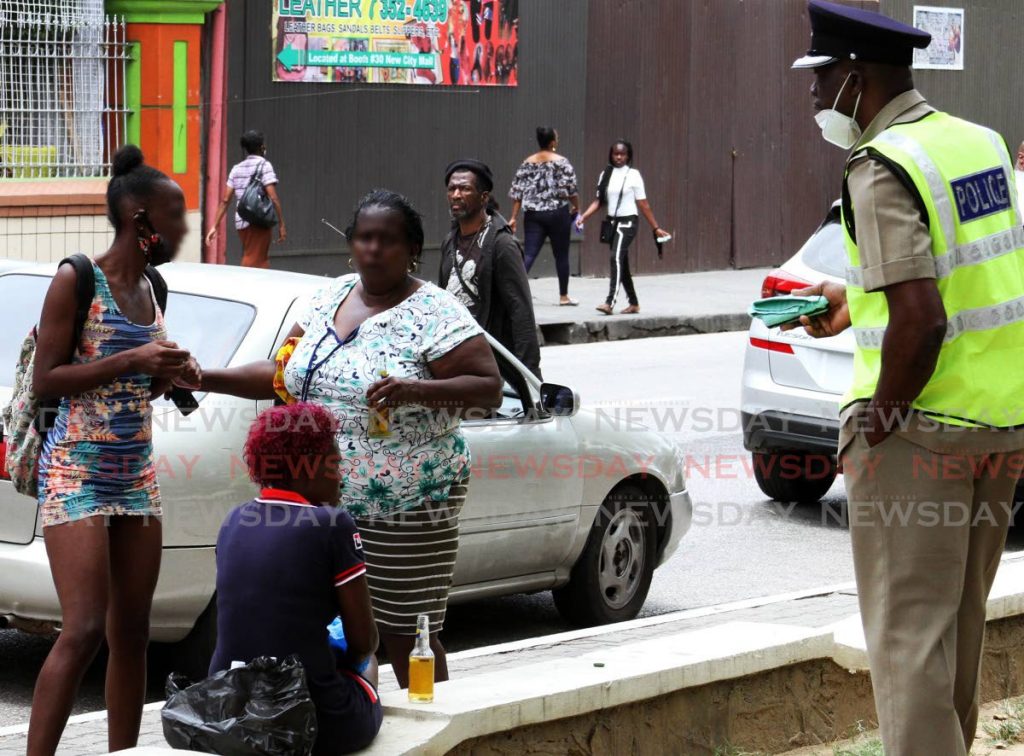 GO HOME!: Port of Spain Division head, Snr Supt Daniel Moore, chastises a group of women drinking beer along the Brian Lara Promenade in Port of Spain on Friday. PHOTO BY ANGELO MARCELLE - ANGELO_MARCELLE