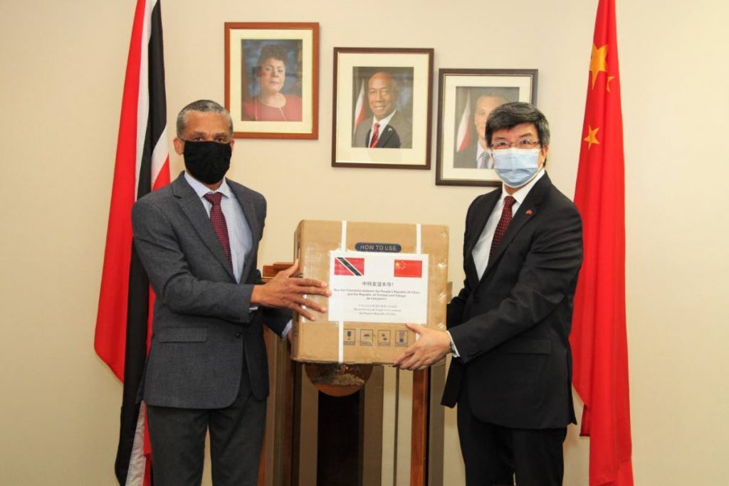 Minister of Foreign and Caricom Affairs Dennis Moses, left, is presented with a donation of personal protective equipment by ambassador of China to TT Song Yumin at the ministry’s office in St Clair on Friday.  - 
