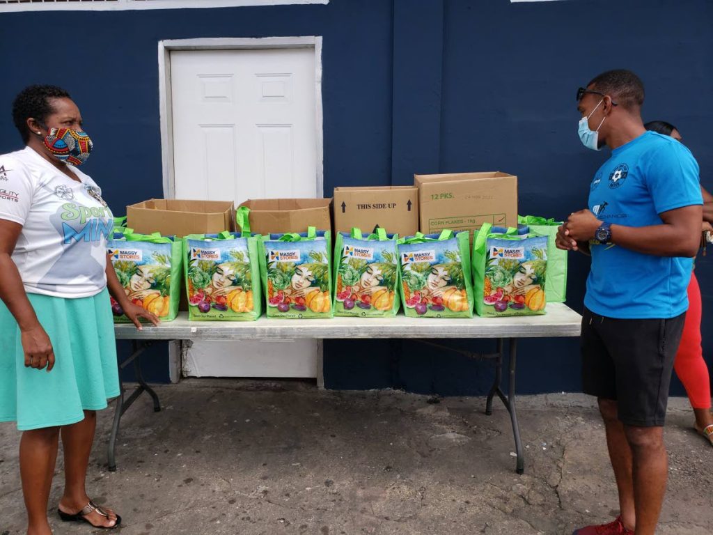Akim Armstrong (right) of the Can Bou Play Foundation during a hamper distribution in his Belmont hometown recently. - 