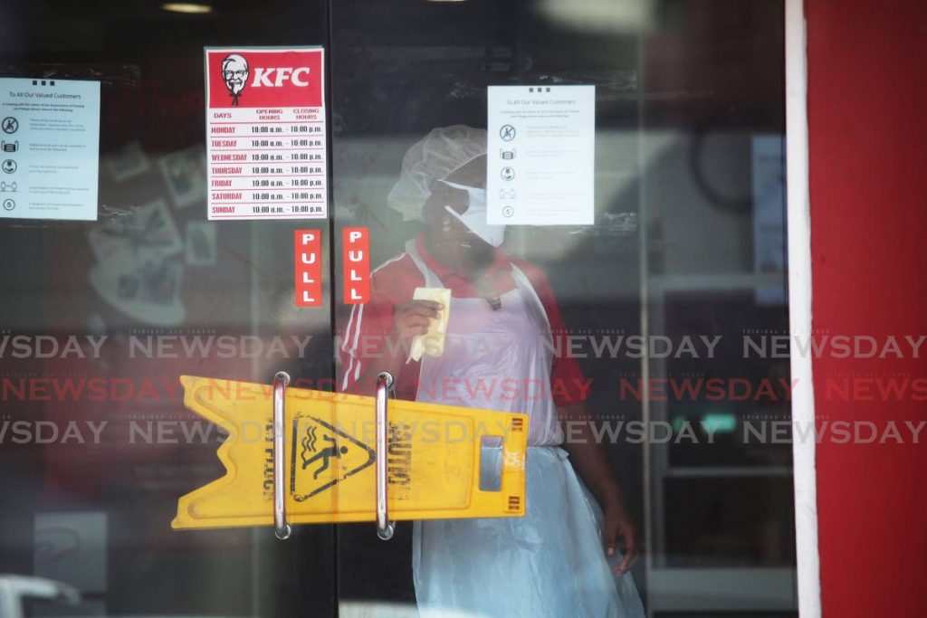 A KFC worker santizing the Coffee street San Fernando outlet - Lincoln Holder