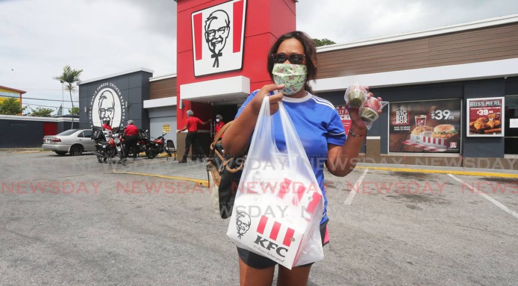 Paula Mohammed shows off her purchase as she was the first customer at the KFC La Romaine as phase one is implemented which allowed food establishments to be open as we deal with covid19 - Lincoln Holder