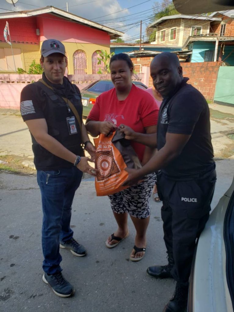 Law enforcement consultant Paul Nahous, left and a member of the police Inter Agency Task Force give a food hamper to a Laventille resident last Saturday. 

PHOTO COURTESY PAUL NAHOUS - Shane Superville