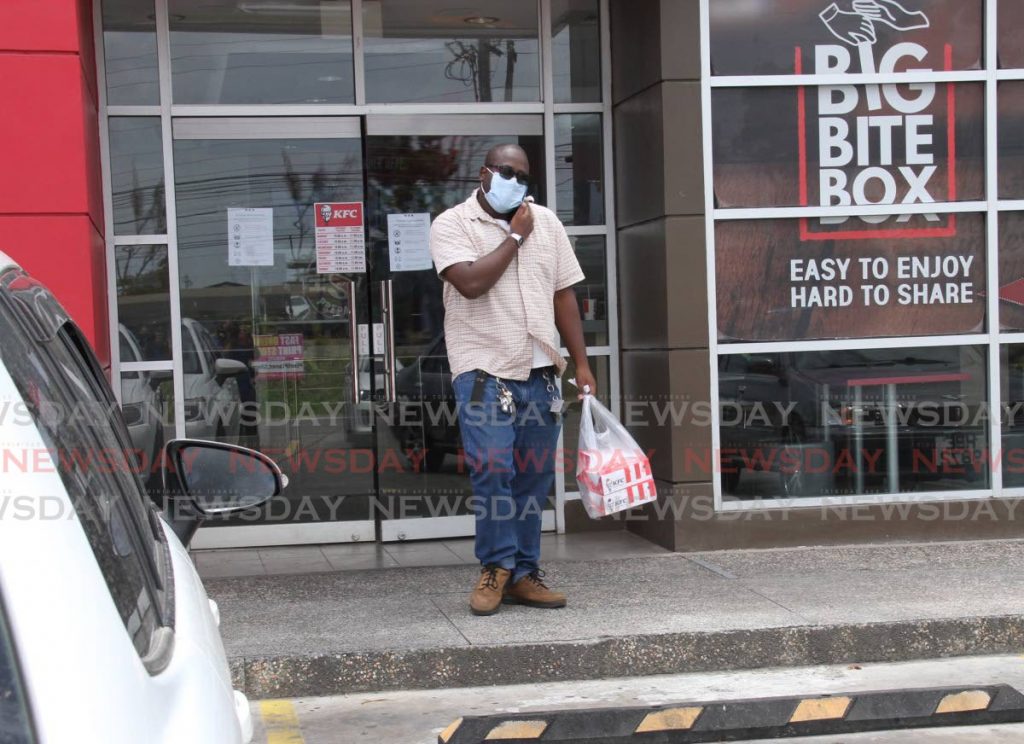 FOOD IN HAND: A man leaves KFC at Xtra Food Plaza in Charlieville after purchasing two boxes of chicken and chips on Monday. PHOTO BY VASHTI SINGH - 