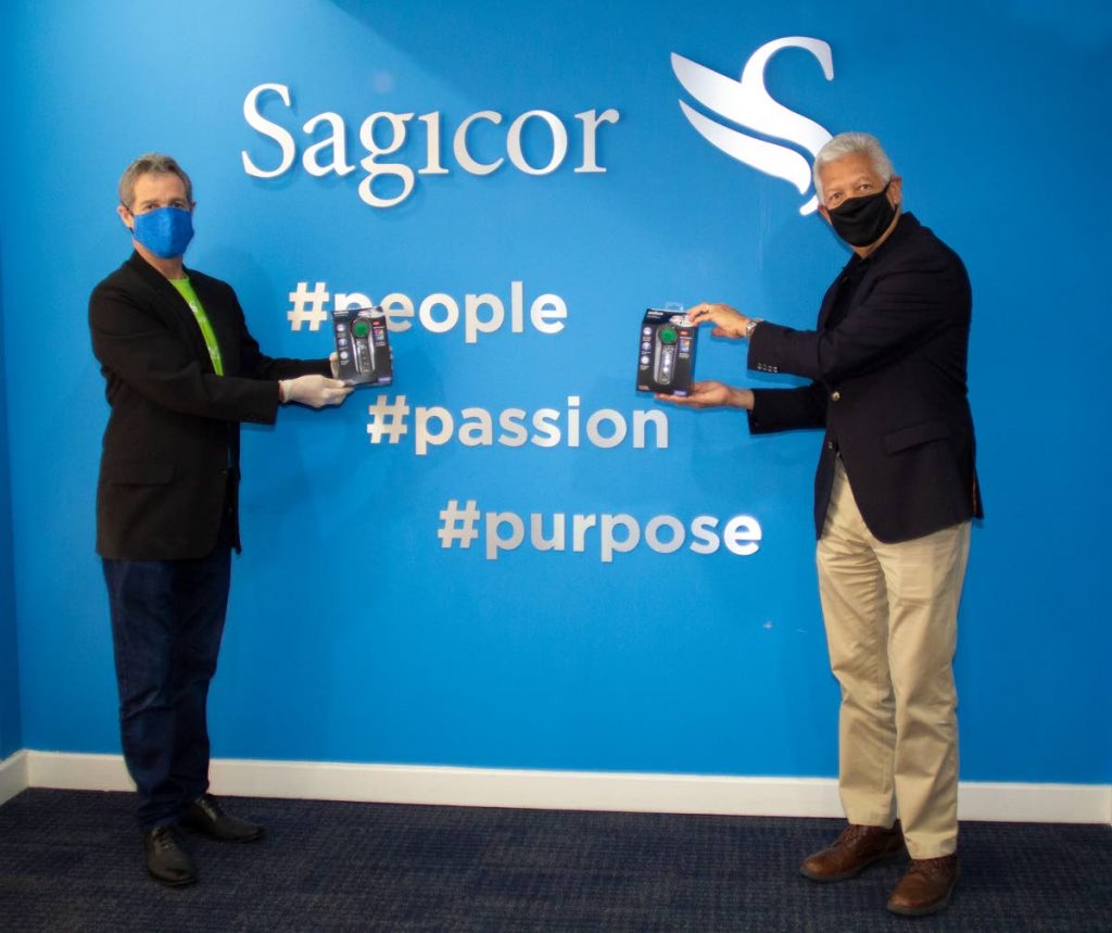 HELPING HAND: Gerard Scott, Manager of Business Development at Sagicor Life Inc, hands over touchless thermometers to Port of Spain Mayor Joel Martinez, right, at Sagicor’s Head Office in Port of Spain.  PHOTO COURTESY SAGICOR LIFE INC  - sagicor 