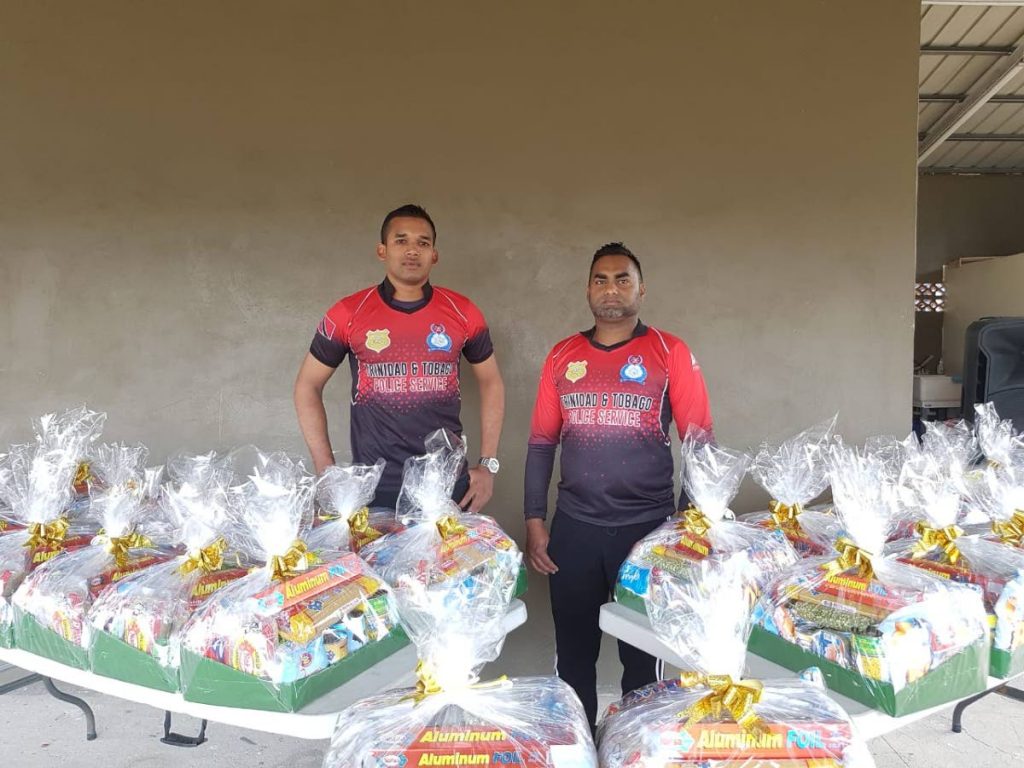 Derek Nancoo, left, and Amir Khan of the TTPS cricket section stand next to hampers that were distributed to families impacted by the covid19 pandemic.  - 