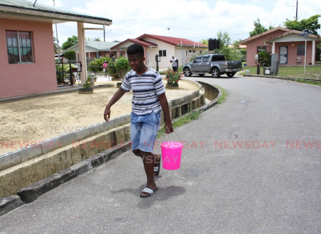 Tyrese Mc Millan takes a bucket of water to his home in a three-floor apartment in phase three Greenvale Park, La Horquetta. - 