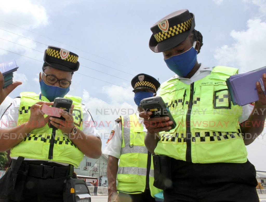 File photo: Traffic wardens check out their handheld ticketing devices at the launch of the demerit point and traffic ticketing system on the Audrey Jeffers Highway in Port of Spain in May. Photo by Angelo Marcelle