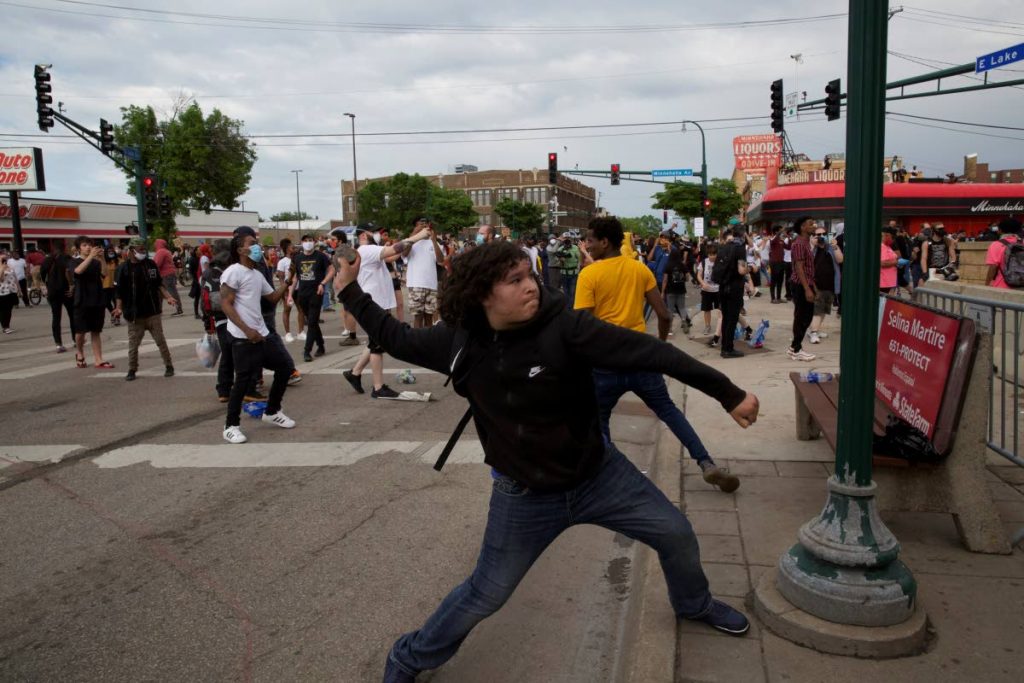 A man throws a rock at the Minneapolis police 3rd Precinct during a protest on May 27 in Minneapolis against the death of George Floyd while Minneapolis police custody earlier that week. - AP PHOTO