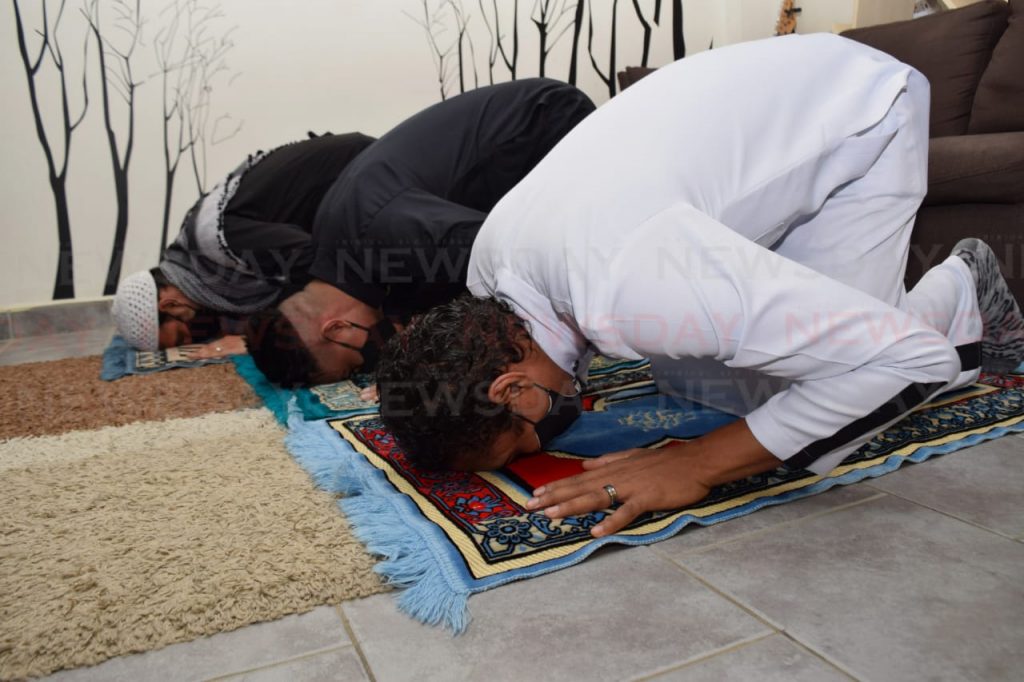 Dr Muhammad Rahman, left, Zaleef Mohammed and Dieter Gaskin demonstrate the Sujud prayer position at their home.