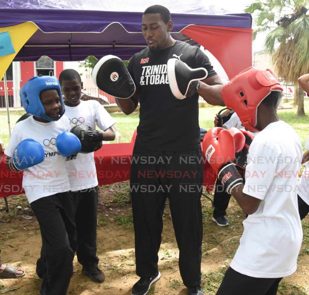 In this June 21, 2019 file photo, TT boxer Nigel Paul teaches boxing techniques to two boys during Olympic Day 2019 at Lord Harris Square, Port of Spain. - 