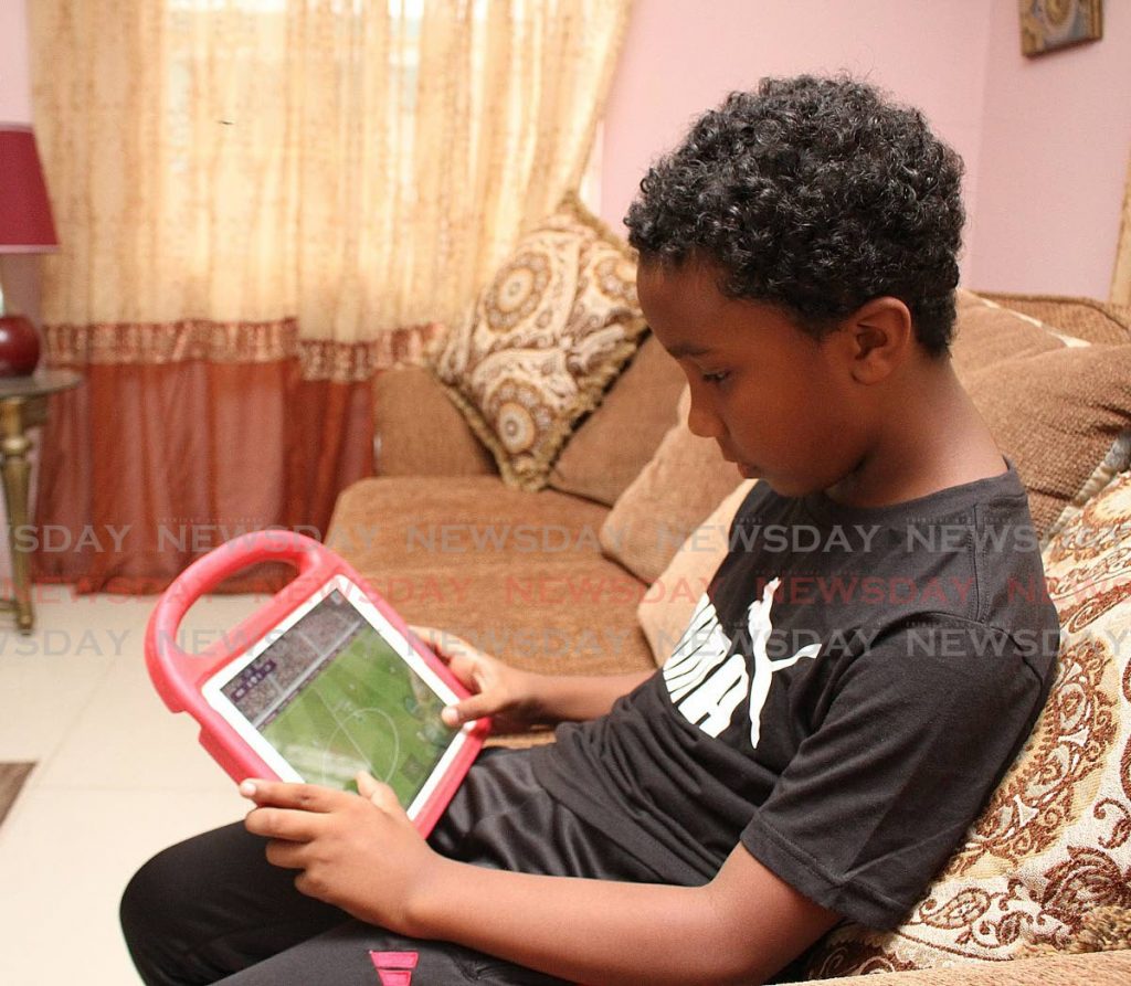 Kymani Dematas relaxes by playing a football game on his tablet at home in Santa Rosa Heights, Arima. - 