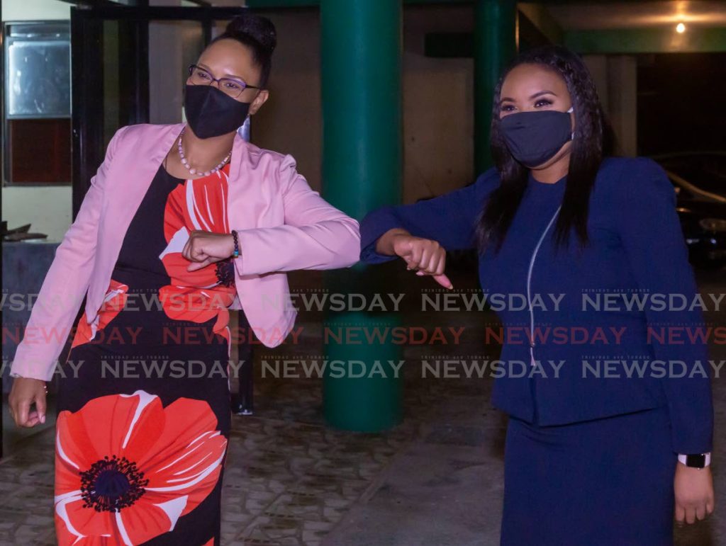 BACK AGAIN: Tobago East MP Ayanna Webster-Roy, left, and Tobago West MP Shamfa Cudjoe, right, touch elbows after being approved by the PNM screening committee on Sunday to fight their respective seats in the next general election. PHOTO BY DAVID REID  - 