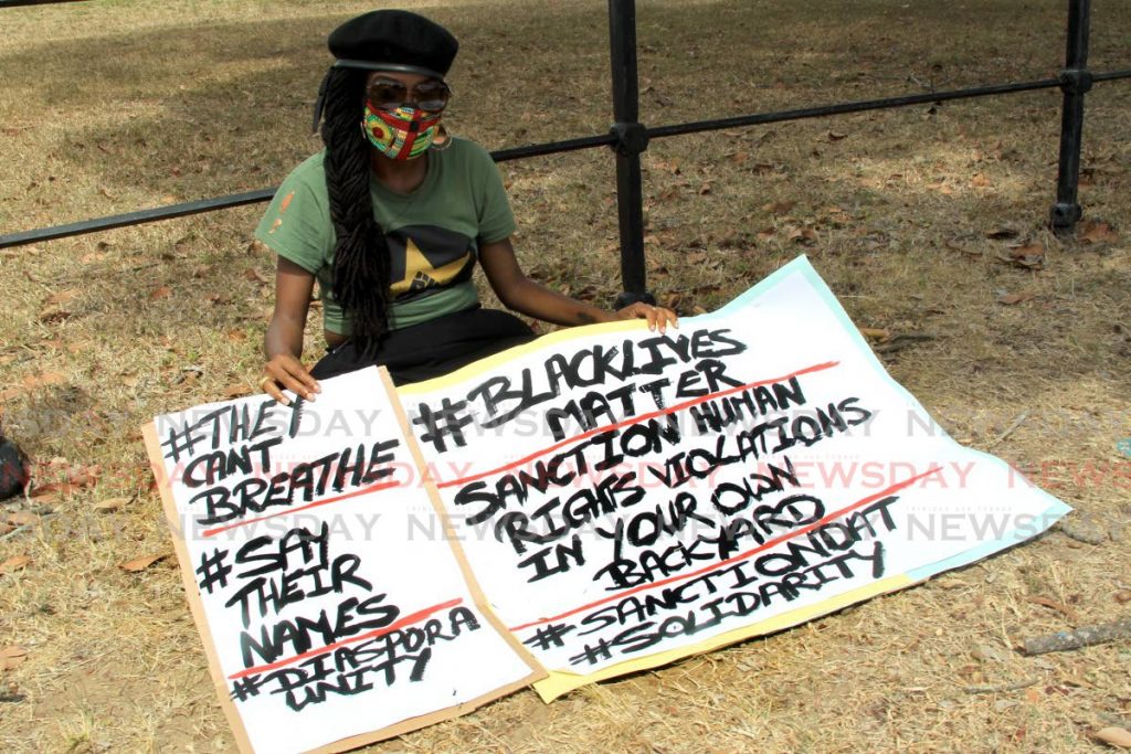 In this June 4 file photo Abeo Jackson sits on the grass at the Queen’s Park Savannah, Port of Spain, opposite the US embassy with posters protesting the killing of George Floyd and other black people in the US.  - ROGER JACOB