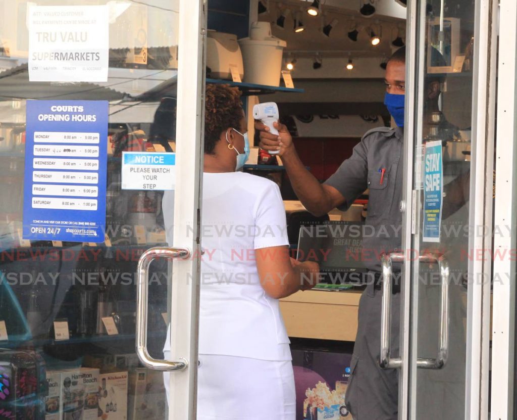 A security guard scans the temperature of a person as she enters the Courts Store on Frederick Street, Port of Spain on June 2. The workforce and the customers should be at the centre of companies’ plans to recover from the restrictions and fallout caused by the covid19 pandemic. - ROGER JACOB