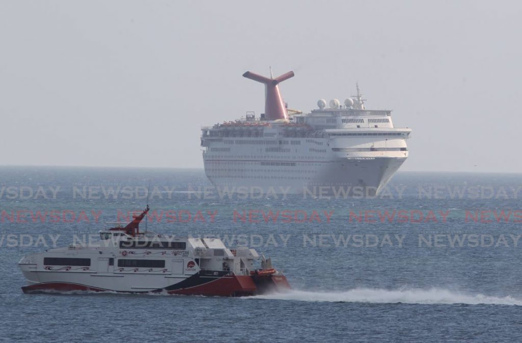 The Carnival Fantasy cruise ship, right, is anchored offshore at the Port of Port of Spain as the MV Trini Flash water-taxi sails away on its routine voyage to San Fernando on Thursday. - ROGER JACOB