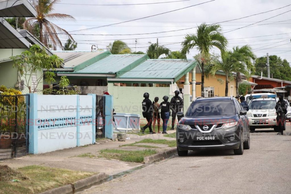 The female murder suspect is led away by police from a home in La Horquetta on Sunday afternoon. - JEFF K MAYERS