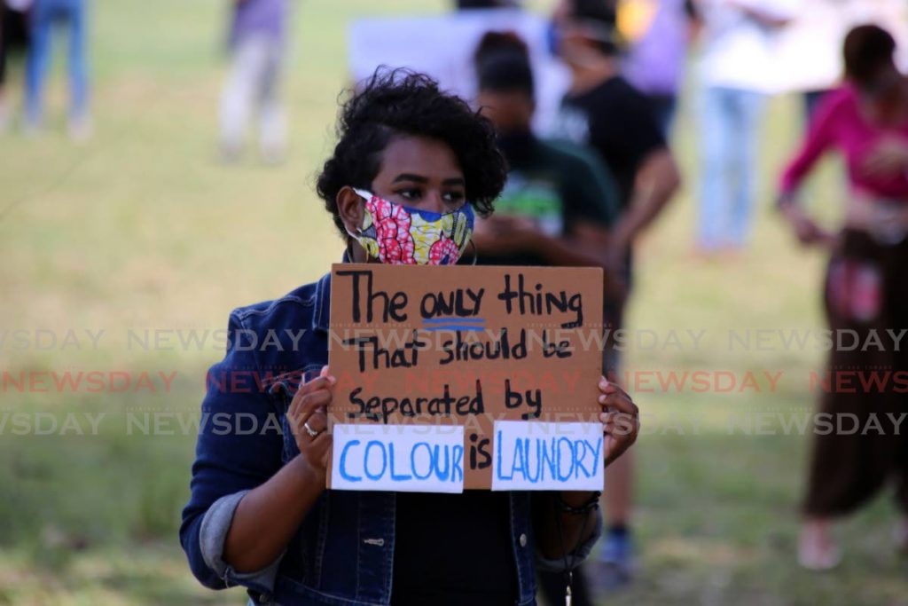 A protester makes a statement on racism with a sign at the Black Lives Matter protest, Queen's Park Savannah, Port of Spain on June 8. - 