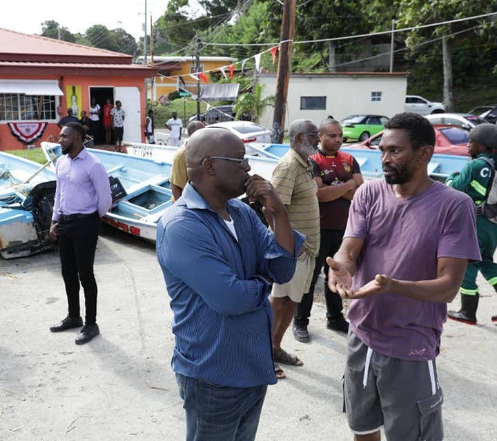 Former THA chief secretary Kelvin Charles, front left, chats with a fisherman last year after Tropical Storm Karen damaged a number of boats on the island. PHOTO COURTESY THA - 