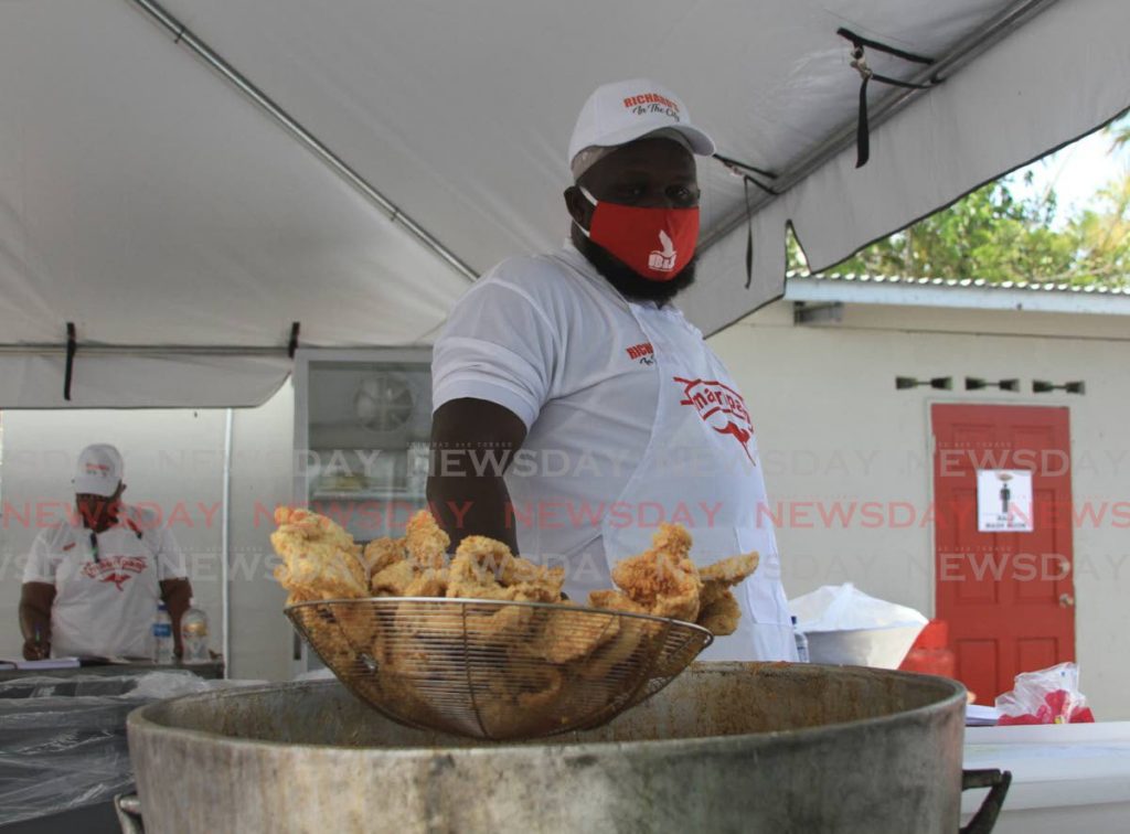 A staff member at Richard's Bake and Shark takes the fish out the pot at the opening on the Western Main Road, St. James. 2020.06.11 - Ayanna Kinsale