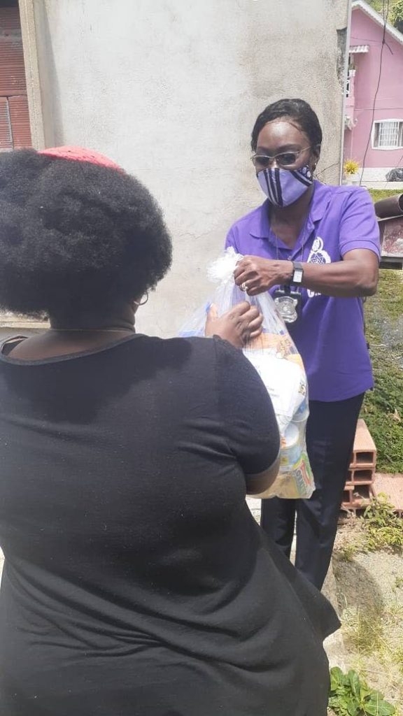 A member of the Community Policing Unit distributes a hamper during an outreach initiative last month.  - 