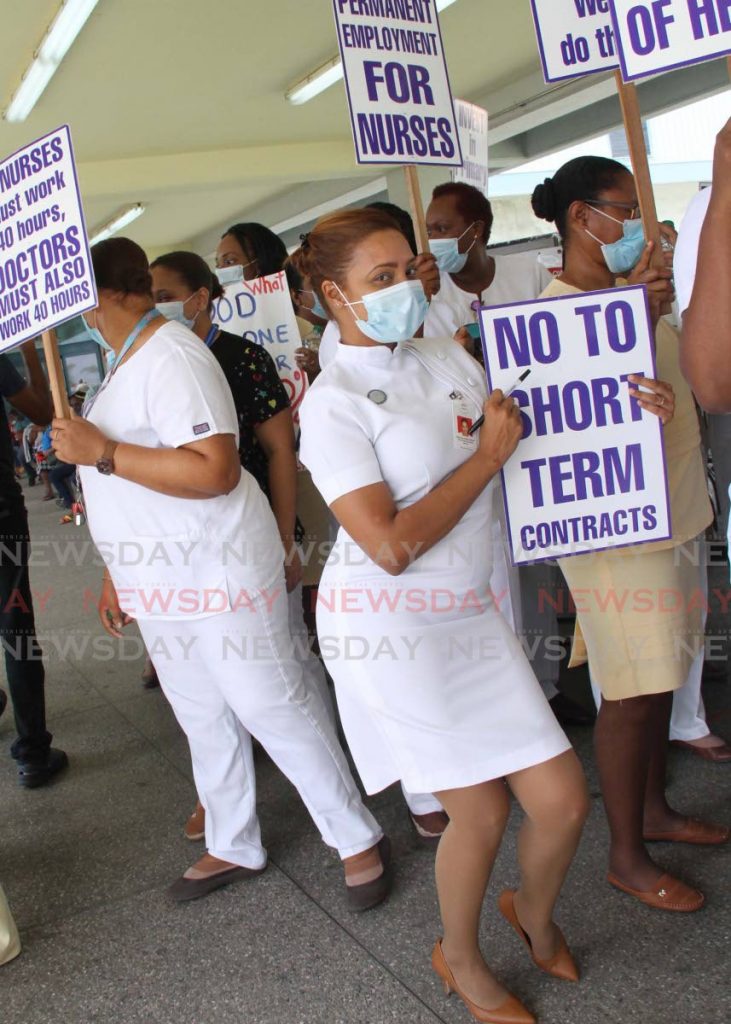 LOOK AT ME: The nurse in the middle poses with her placard as she and other health care workers protested on Thursday at the San Fernando General Hospital. PHOTO BY VASHTI SINGH - Vashti Singh