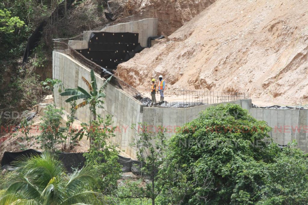 Workers stand near the southern perimeter wall of the housing development at Upper Bournes Road, St James. - Angelo Marcelle