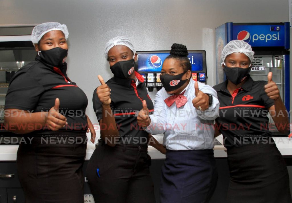 Hazel Daniel of Caribbean Cinemas 8, second from right, smiles with her staff, from left, Mickela Ellis, Keifa Denoon and Melissa Garcia as they reopened for business on Thursday. - Ayanna Kinsale