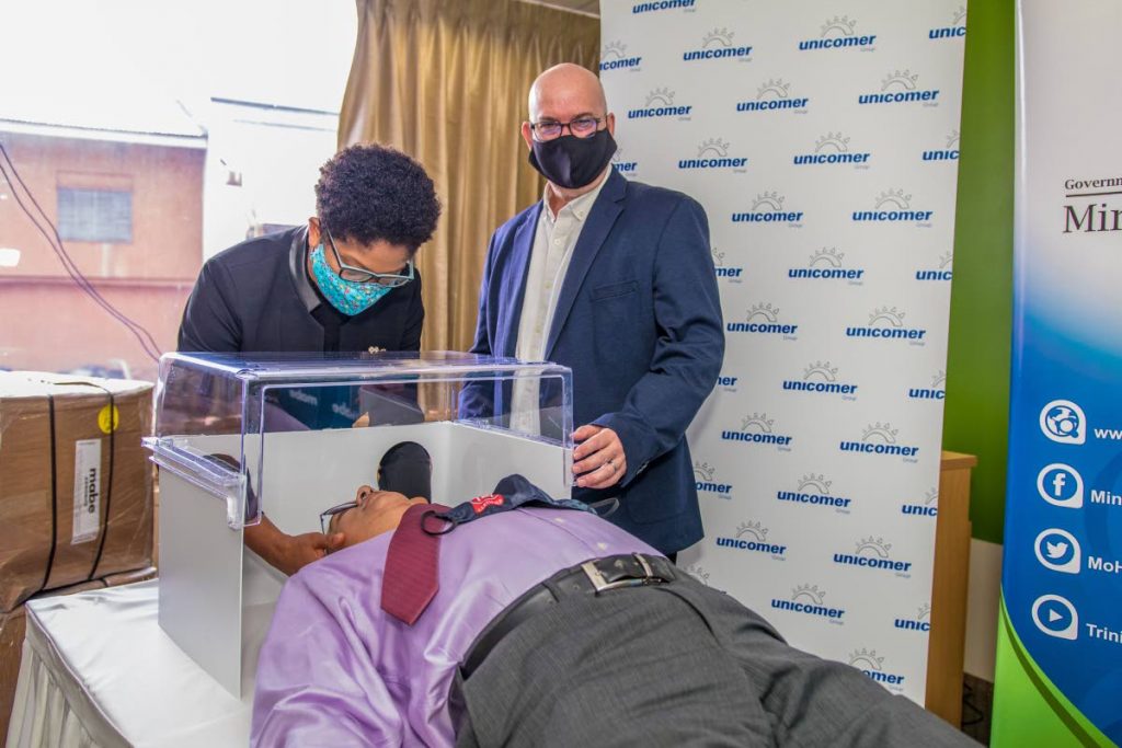 DEMONSTRATION: Health Minister Terrence Deyalsingh is shown by national administratir of nursing services, Betty Ann Pilgrim, and Unicomer (Trinidad) managing director Clive Fletcher how the Aerobox is used. PHOTO COURTESY UNICOMER (TRINIDAD) - 