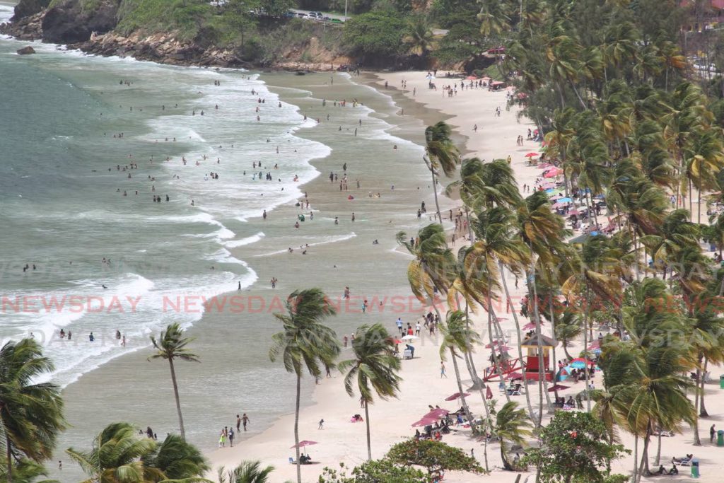 Maracas Bay seen from a distance, with many people dotting the water as they bathed.  - ROGER JACOB