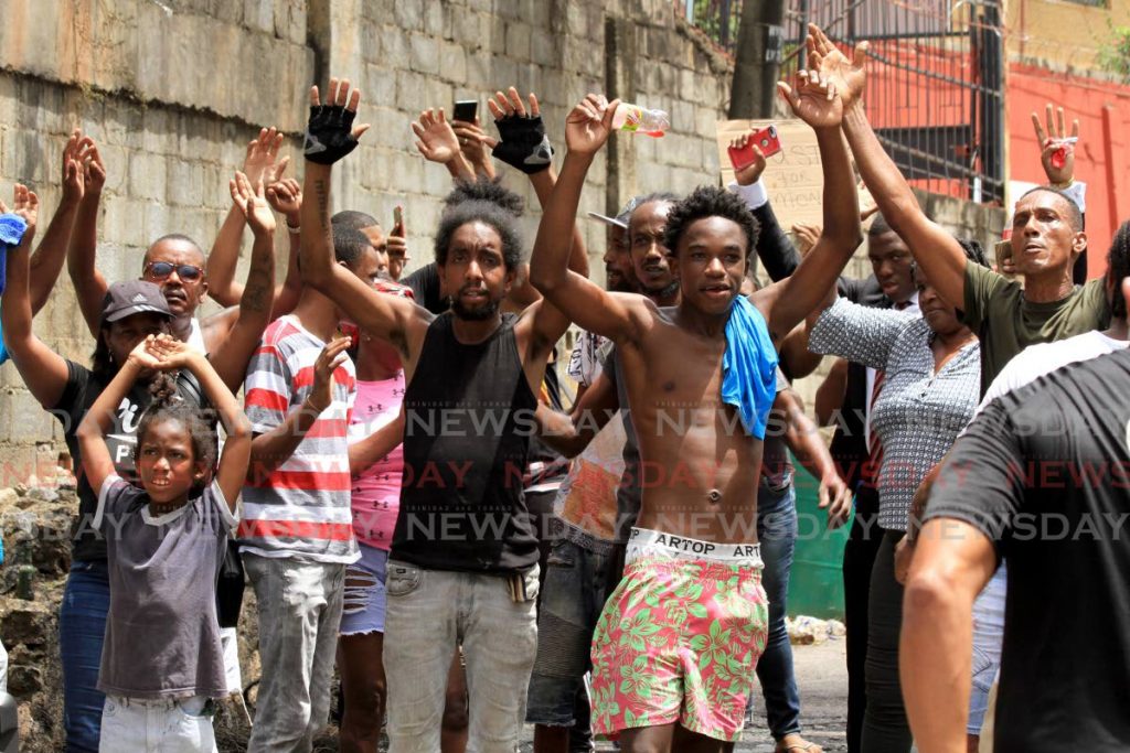 HANDS UP!: Morvant residents put their hands in the air in protest over the killing of three men by police on Saturday. - Ayanna Kinsale