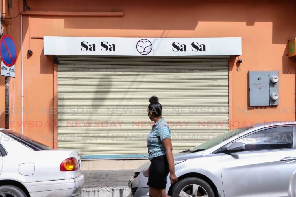 A passerby walks past a store on Charlotte Street, Port of Spain which closed on Thursday after police dispersed a group of protesters. PHOTO BY JEFF MAYERS - 