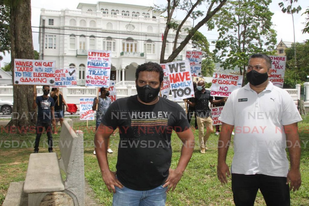 Teron Mohan, interim president of the Barkeepers and Owners Association (left) and  members of the association protest at the Queen's Park Savannah opposite the Office of the Prime Minister in July.  Photo by Roger Jacob